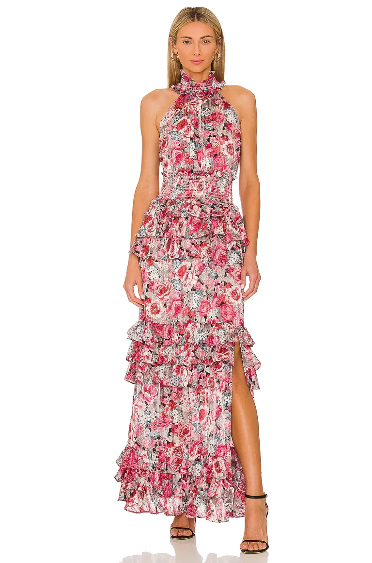 Model wears a vibrant ruffled dress with a halter neckline and a floral pattern. 
