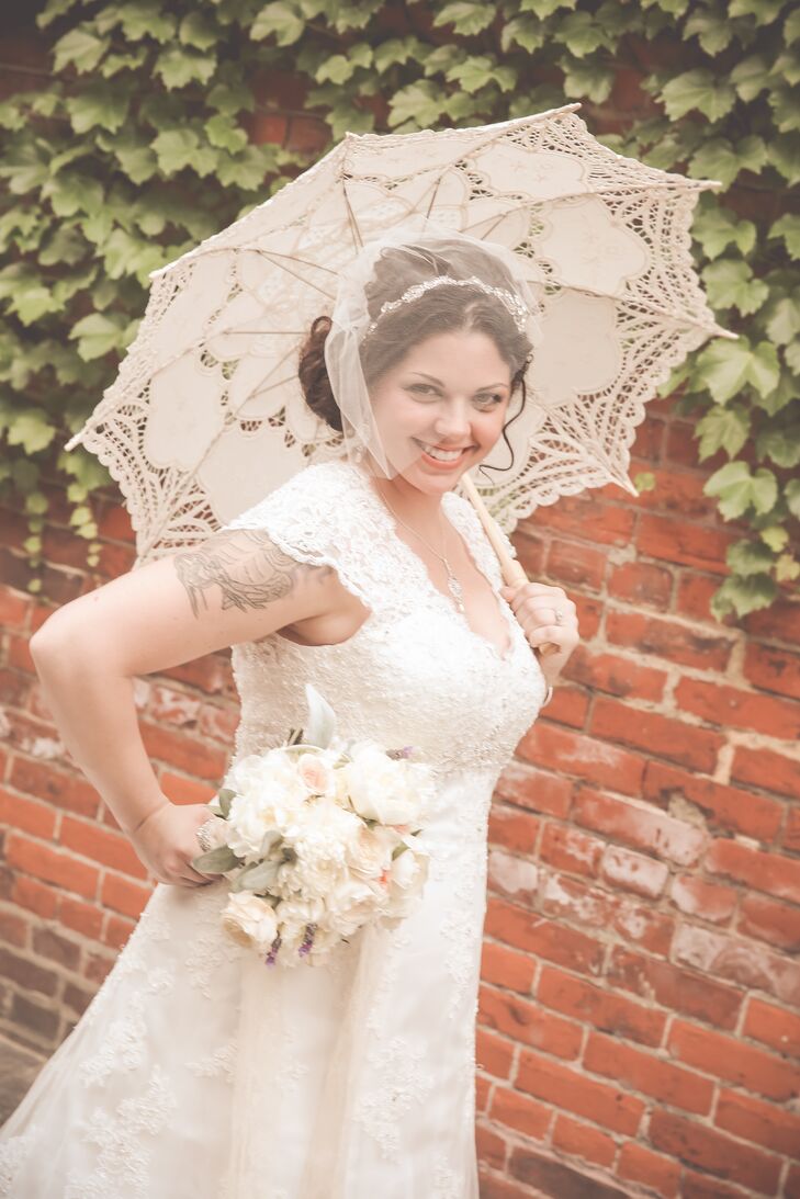 In keeping with the vintage theme, Jessica accented her wavy updo with a silver headband and classic blusher veil. She carried a lace parasol to accentuate her lace, cap-sleeve wedding dress.