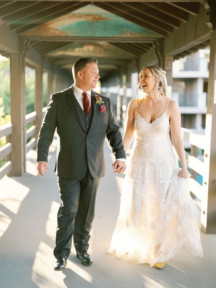 Bride in a Fitted A-Line Dress and Groom in Dark Gray Suit Hold Hands