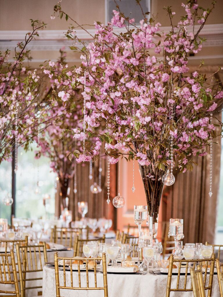 tall wedding centerpieces with pink cherry blossom branches decorated with votive candles hanging from glass bead strands