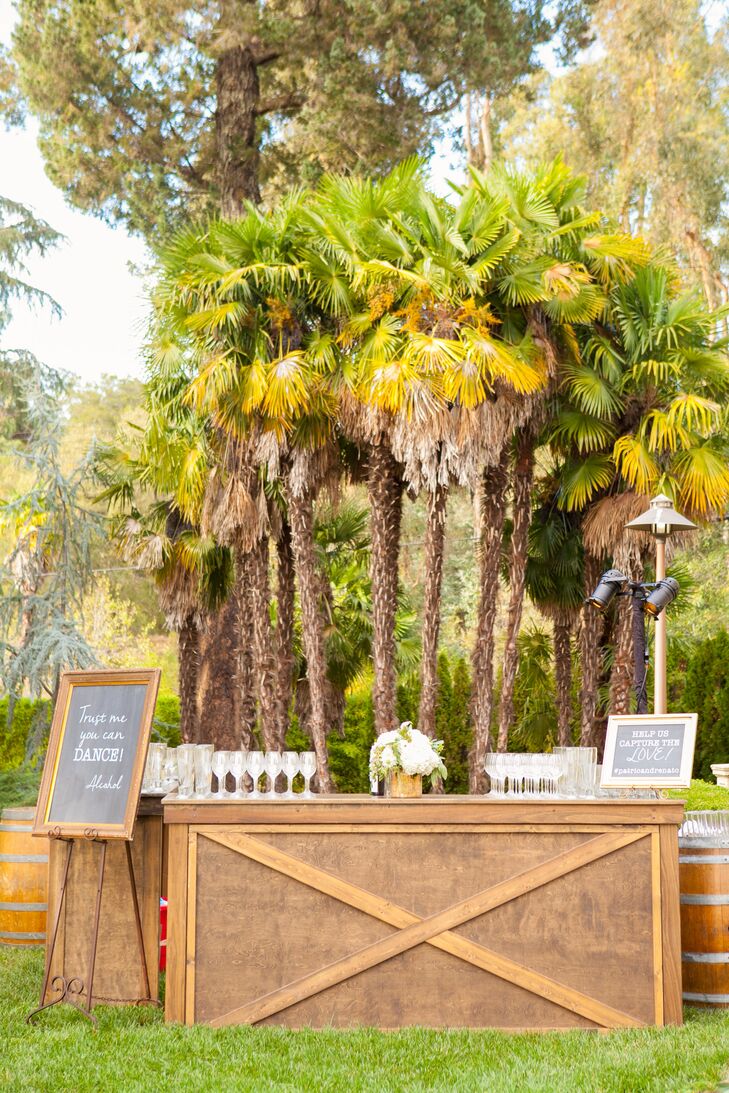 After the outdoor ceremony, guests stopped at the textured kraft-wood bar for a glass of champagne. The bar's decor—white blossoms and greenery in a gold mercury-glass vase—were mirrored on the dining tables.