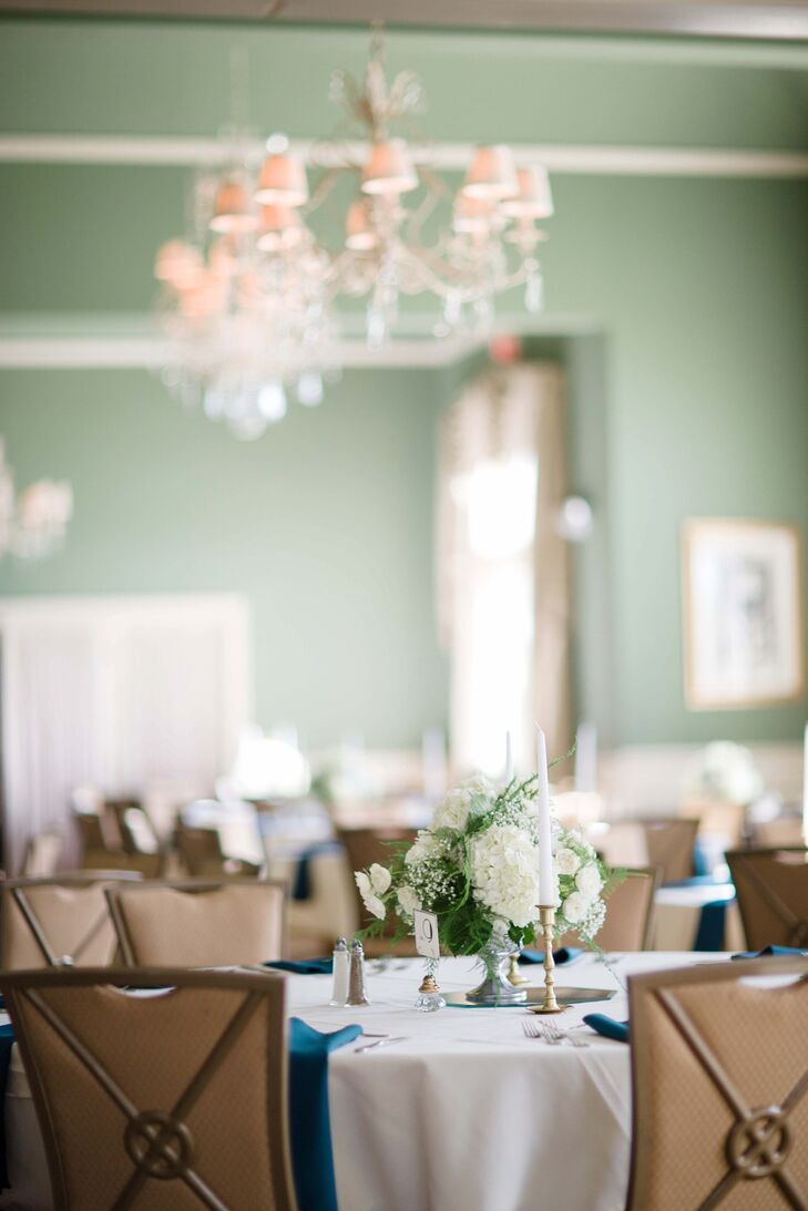 Centerpieces filled with white roses, hydrangeas and baby's breath elegantly decorated white-covered dining table tops at the reception.