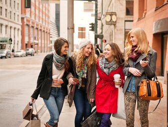 four women walking arm in arm in downtown denver