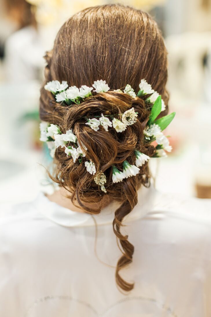 After All Ways Hair Studio styled her curls into a chic updo, they added a few natural accents to match her bouquet. Small white flowers were braided into it as a single curl fell along her back.