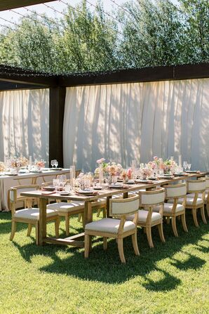 Long Tables at Outdoor Venue With Pastel Flowers Under String Lights