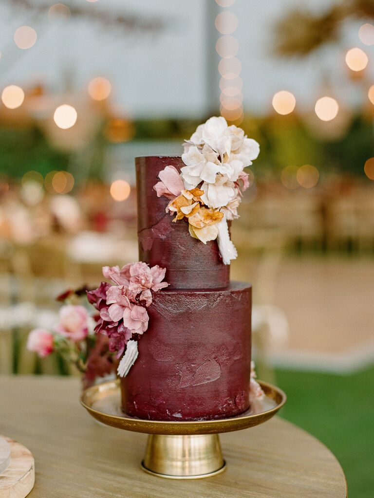 two tier brown wedding cake with blush, white and pale orange flowers on gold cake stand