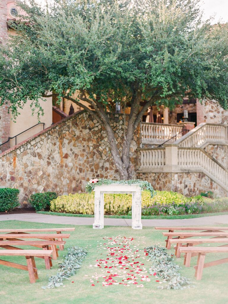 outdoor wedding ceremony with vintage mantel at the altar decorated with greenery and pink flowers