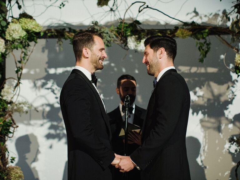 Grooms holding hands smiling