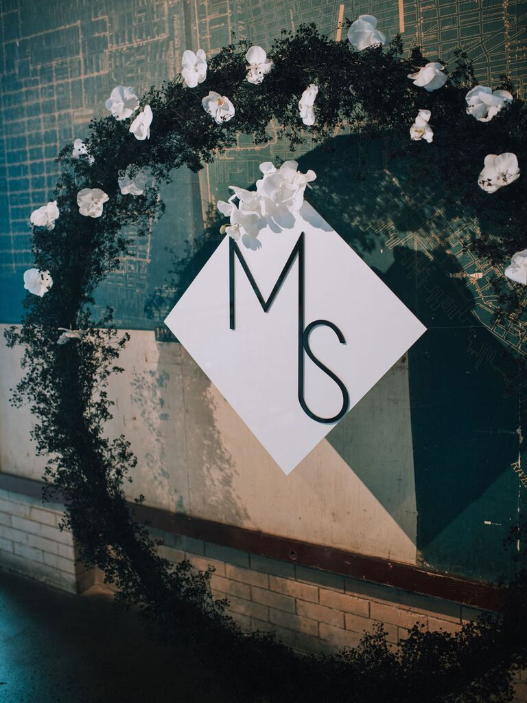 Round floral ceremony arch with white orchids and sleek monogram sign