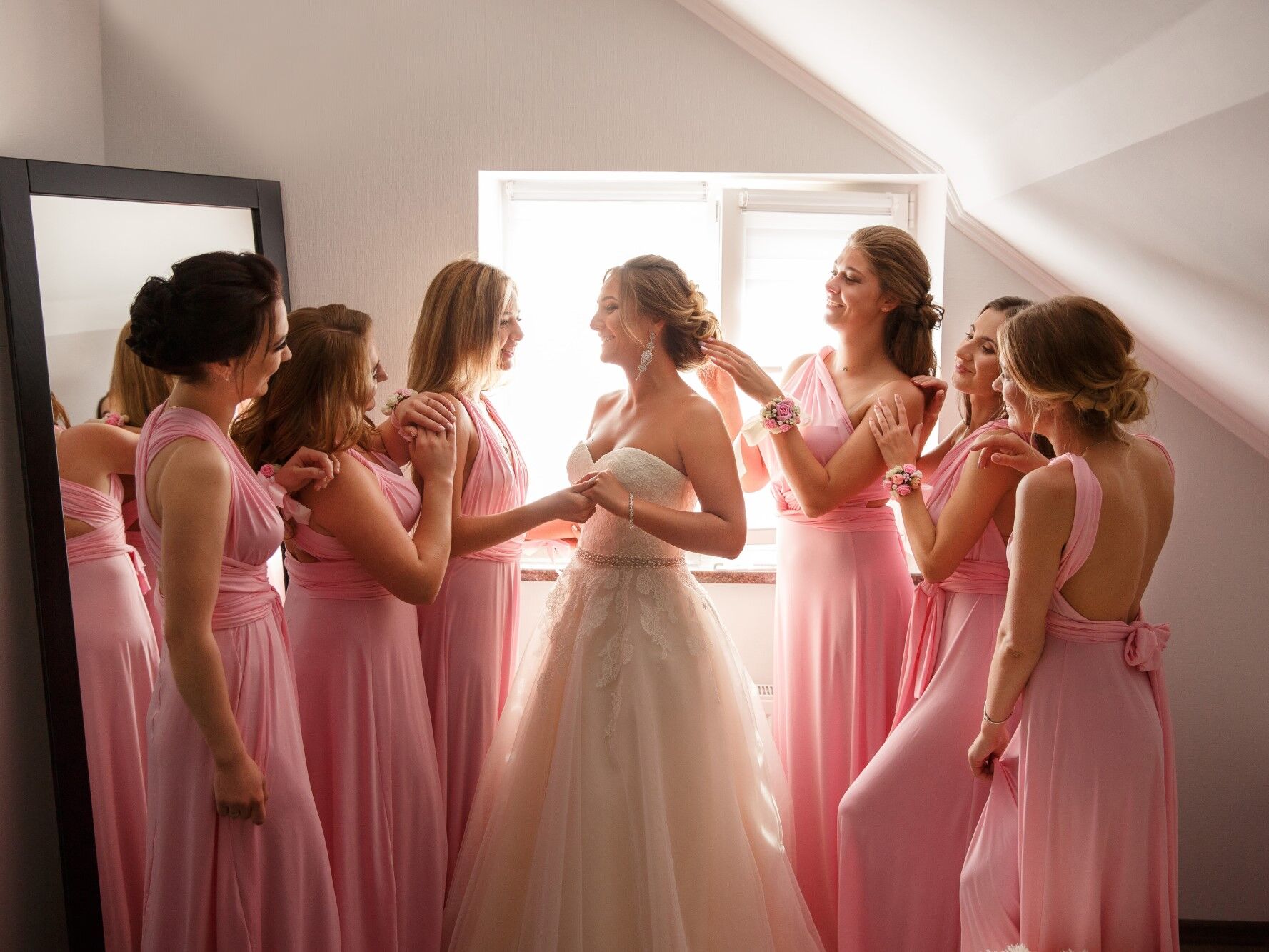 Bride surrounded with a group of bridesmaids who look at her adoringly. 