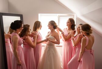 Bride surrounded with a group of bridesmaids who look at her adoringly. 