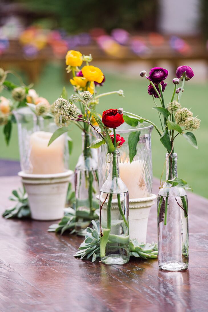 Even though it was raining throughout the day, the couple and their guests were still able to enjoy an outdoor cocktail hour. Some of the wooden tables were lined with candlelights inside vintage planters and clear glass bottles filled with bright ranunculus. Succulents also lined the center of the table.