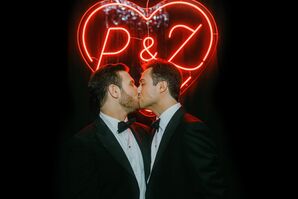 Grooms in Tuxedos Kiss Under Custom Heart-Shaped Neon Sign