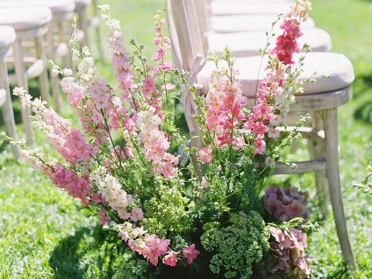 A pink delphinium flower arrangement as a wedding ceremony aisle decoration