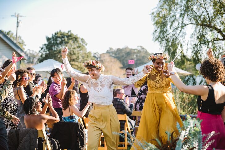 Newlyweds in Unique, Yellow Outfits and Flower Crowns During Recessional