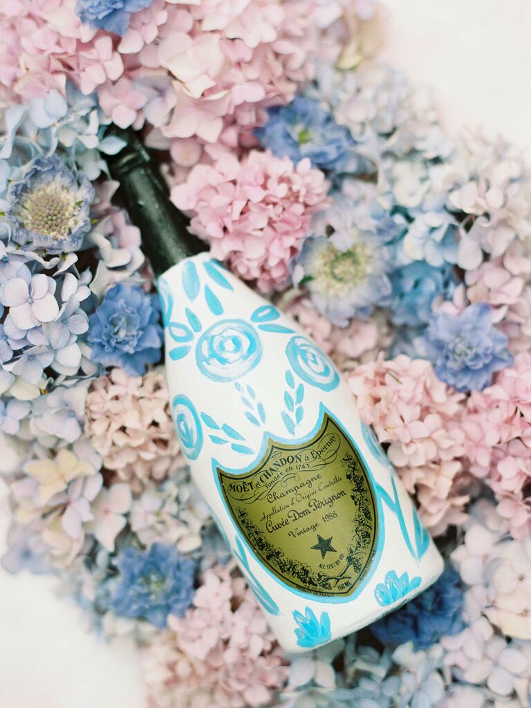 Blue and white bottle of champagne on bed of pastel flowers