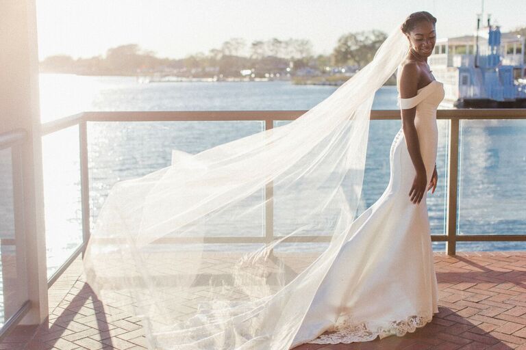 Bride wearing off-the-shoulder dress with veil flowing in the wind