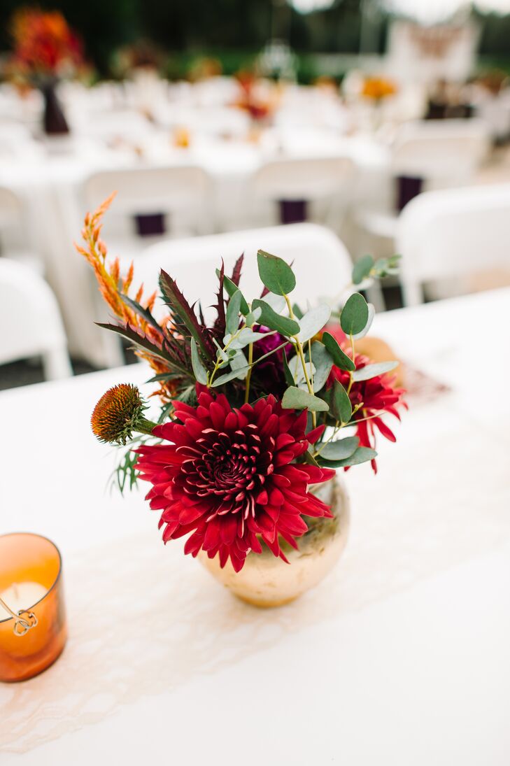 Every arrangement on Shelby and Zack's tablescapes was a little different. 2Birds Events  filled the low gold and tall plum vases with a mix of red, green and burgundy hues to make it feel even more like fall. A specific centerpiece had red dahlias, eucalyptus, scabiosa and leaves.