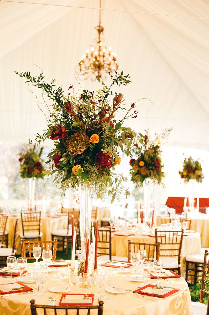 For a rustic-yet-elegant look, Ellie and Adam's florist filled tall clear glass vases with a mix of red and orange roses accented by textured elements like eucalyptus, willow branches, hydrangeas and various greenery.