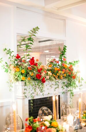 Fireplace Mantle Decorated With Red Roses and Orange Ranunculus