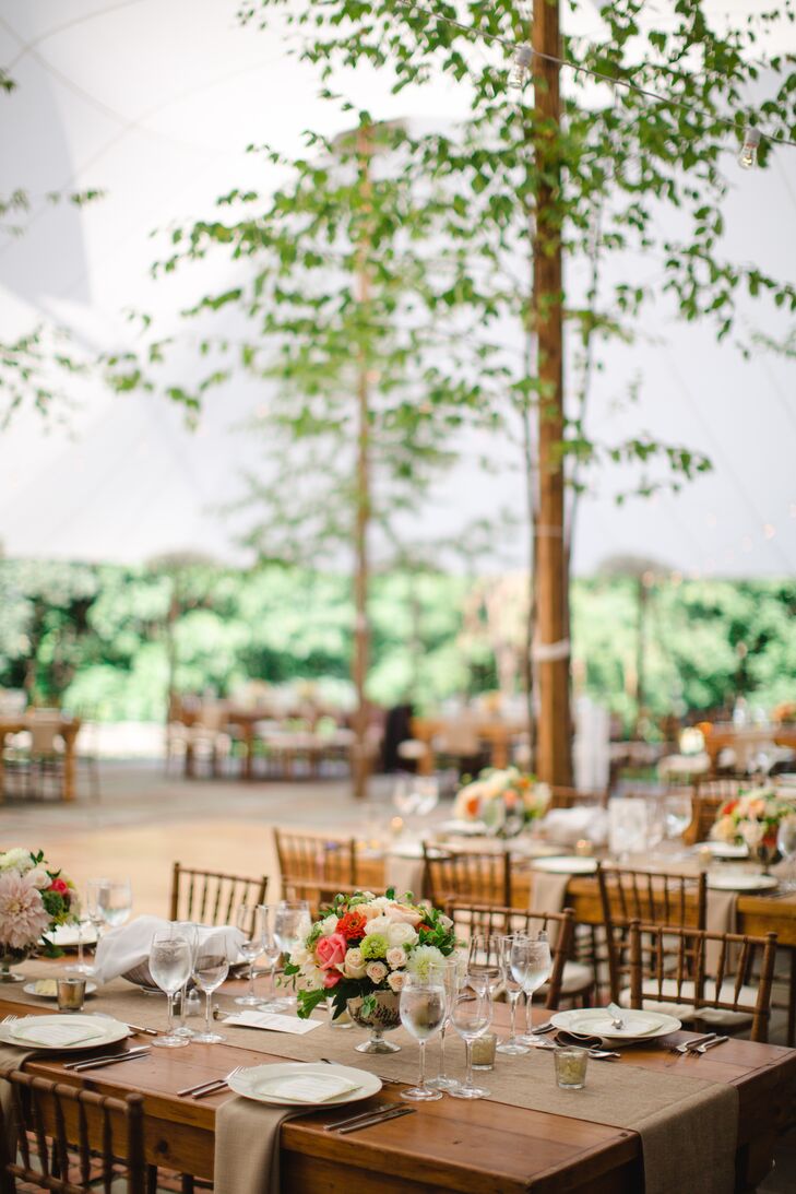 Hannah and Ed made guests feel at home with quaint details like wooden farm tables and burlap linens that exuded warmth, ambiance and family-dinner vibes. Pops of coral in bountiful arrangements of roses, gerbera daisies, dahlias and hydrangeas added a hint of vibrancy to the tablescapes, while votive candles established a feeling of romance and intimacy.