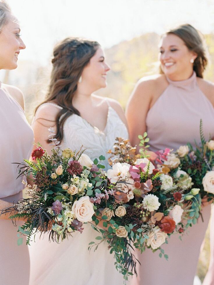 bride and bridesmaids posing together and holding bouquets