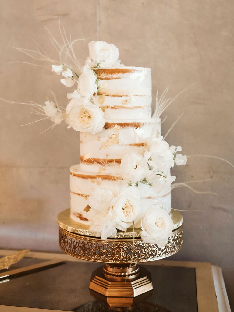 three tier naked wedding cake with white flowers and white ostrich feathers