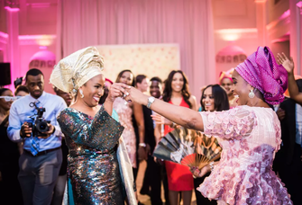 A bride and her wedding guest dance the night away in traditional Yoruba attire.