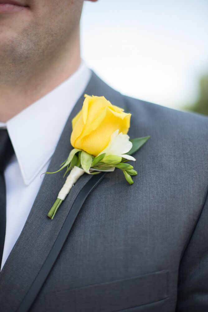 James wore a yellow rose and white freesia boutonniere with his gray wedding suit.