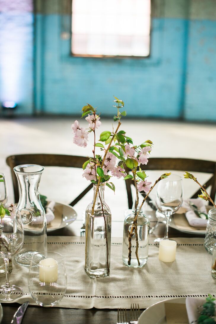 Lauren and Dave envisioned a laid-back affair that felt more like an intimate dinner party than a blowout bash. “I also wanted the evening to have a backyard feel,” says Lauren. “The style was very organic, simple and elegant. We kept the decor to a minimum to allow the character of the venue to shine through.” Wooden farm tables dressed with simple linen table runners and vintage-inspired bottles filled with flowering branches made guests feel like they’d sat down to a family dinner, while warm candlelight infused the industrial space with undeniable ambiance.