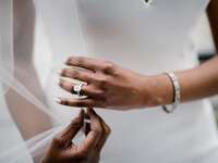 Bride wearing white gold oval-cut engagement ring on wedding day