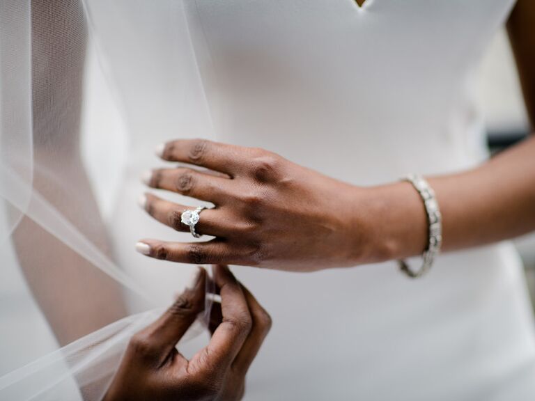 Bride wearing white gold oval-cut engagement ring on wedding day
