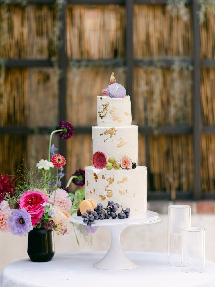 three-tier spring wedding cake decorated with gold leafing and macarons