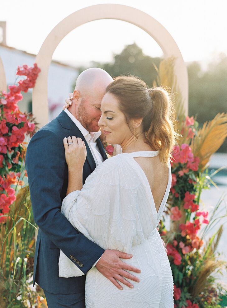 Bride and Groom Share a Hug in Front of Wedding Arch and Bougainvillea