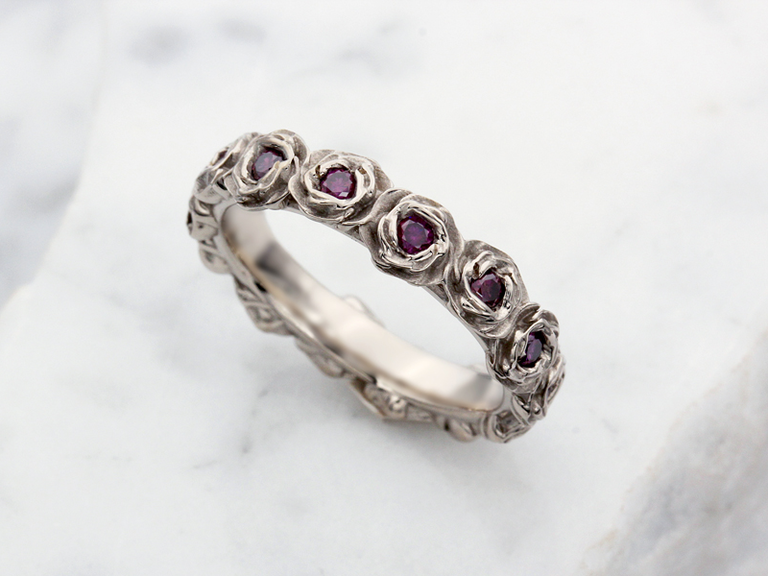 white gold ring in rose design with purple diamonds at center
