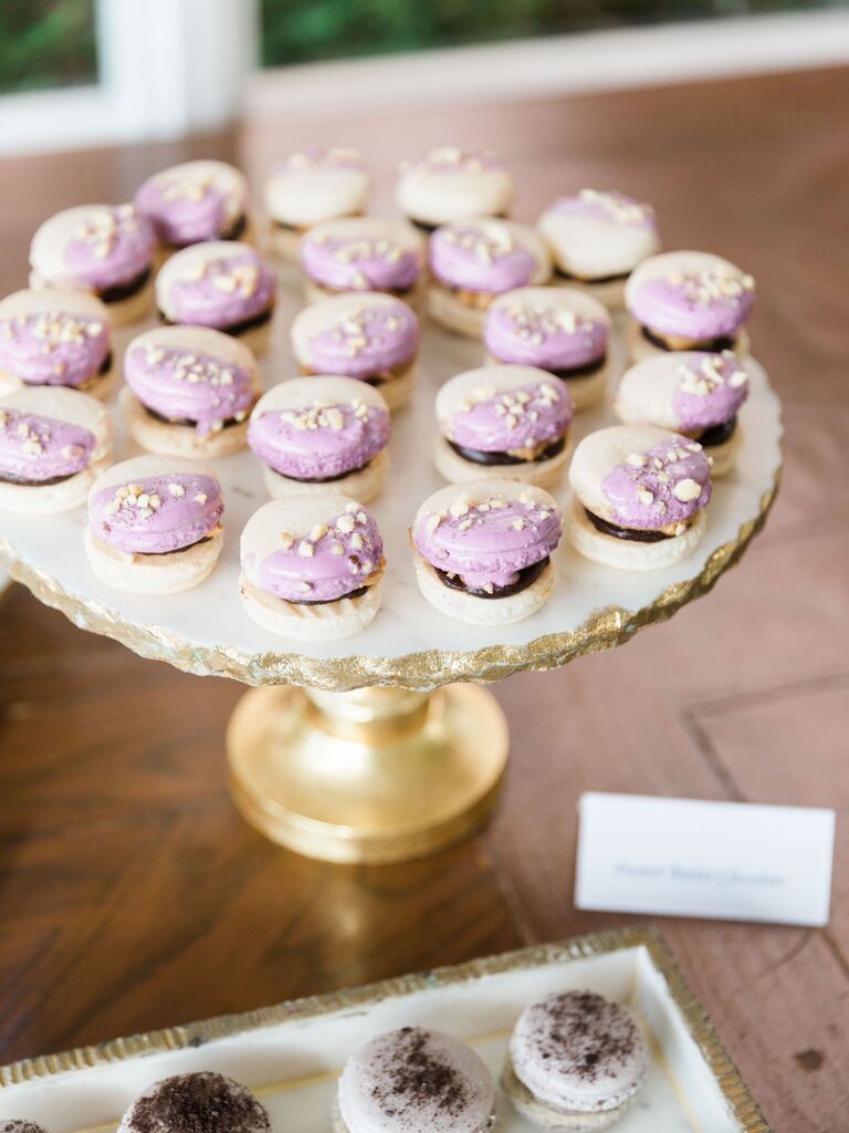 macarons dipped with light purple frosting and almonds arranged on a gold tray