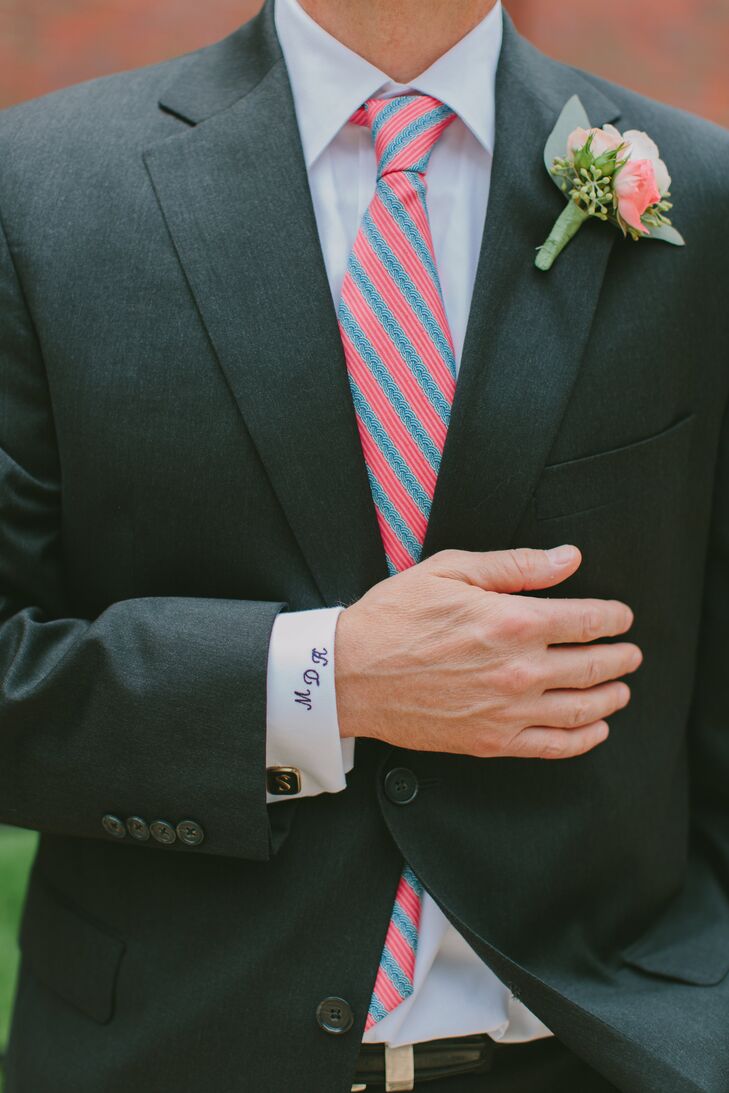 The groom wore a coral spray rose boutonniere. His cuff was monogramed in navy with his initials.