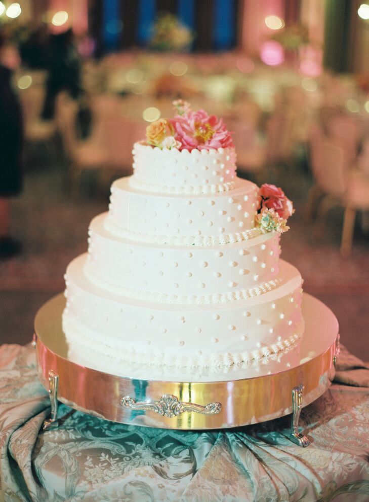 Taking a cue from their decor, Alyse and Dimitry took a classic, yet playful approach to their wedding cake. The Saint Louis Club whipped up a four-tiered confection that was just as easy on the eyes as it was on the palate, with each tier displaying a sweet Swiss dot pattern layered over rich buttercream frosting. As a finishing touch, they added bunches of fresh coral and peach-colored blooms, tying the decadent treat into the wedding’s cheerful spring-inspired decor.