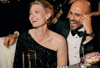 Woman wearing long sleeve one shoulder black sequined wedding guest dress