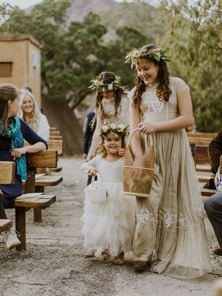 Flower girls wearing boho flower crowns at outdoor wedding ceremony
