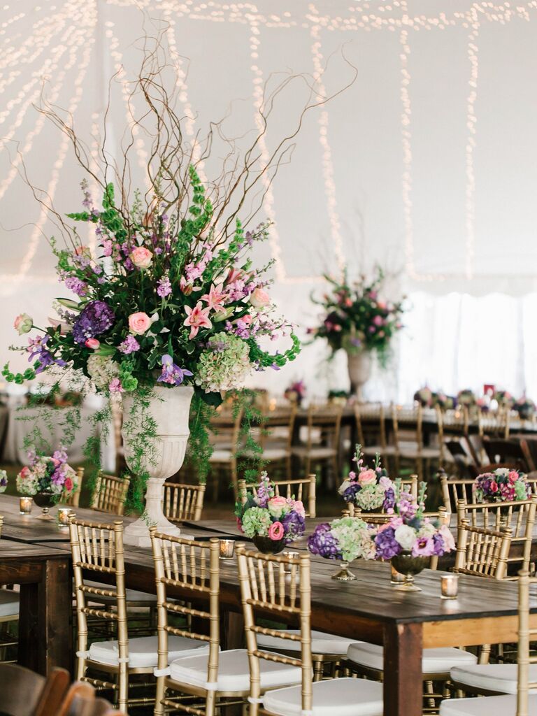 tall wedding centerpiece with pink lilies, purple hydrangeas, greenery and curly willow branches in stone urn