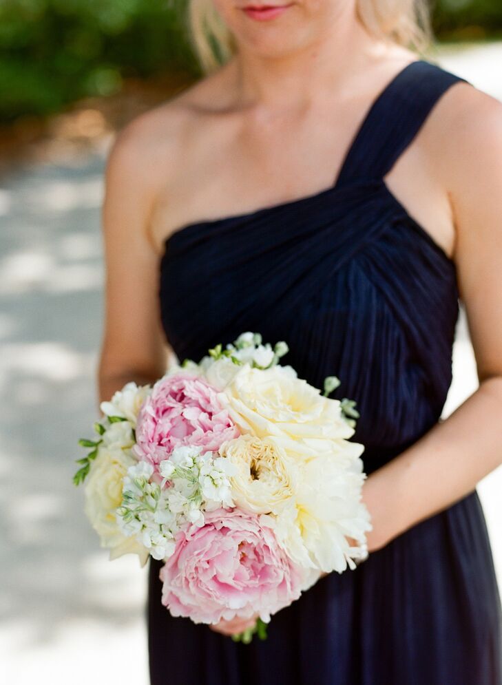 Pale pink peonies mixed with ivory roses and white delphiniums in the bridesmaids' bouquets for a pop of color.
