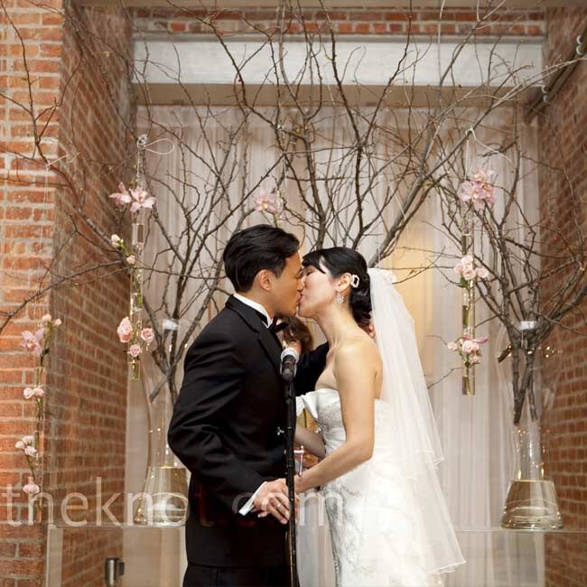 Cherry blossom branches in tall glass vases provided the backdrop for the ceremony.