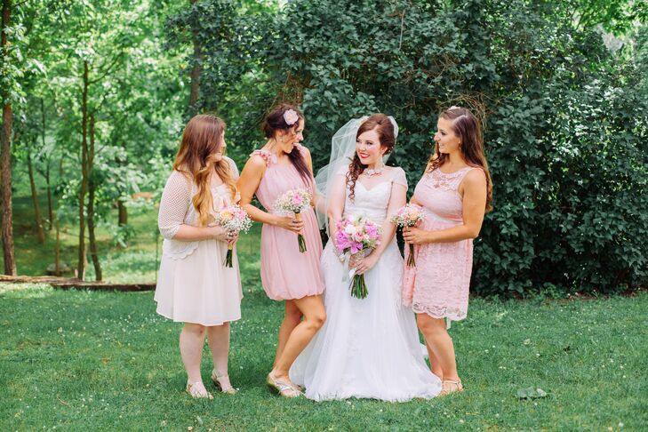 Angie's bridesmaids wore different knee-length dresses in various shades of blush. They all styled their hair down for the day and added floral hair accessories.