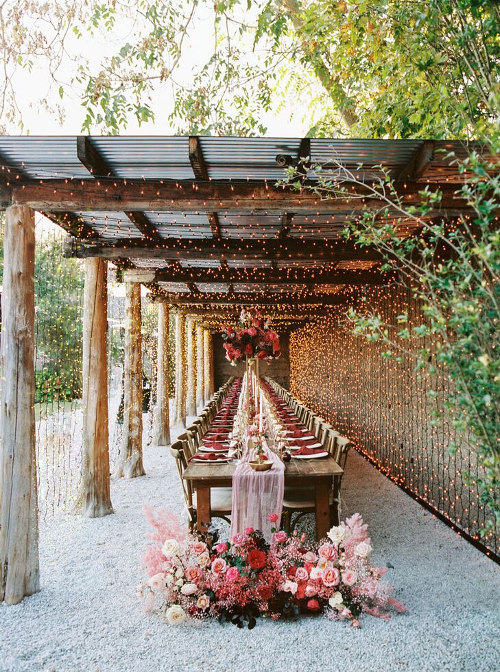 Long Wood Table With Pink Tulle Runner, String Lights Overhead and Flowers