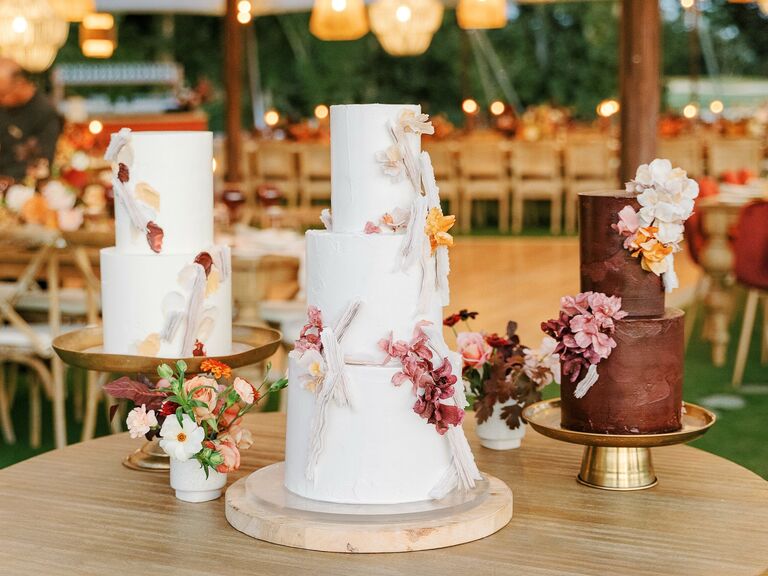 trio of wedding cakes on wooden table at reception