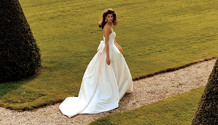 bride in off-the-shoulder wedding dress and groom surrounded by wedding party