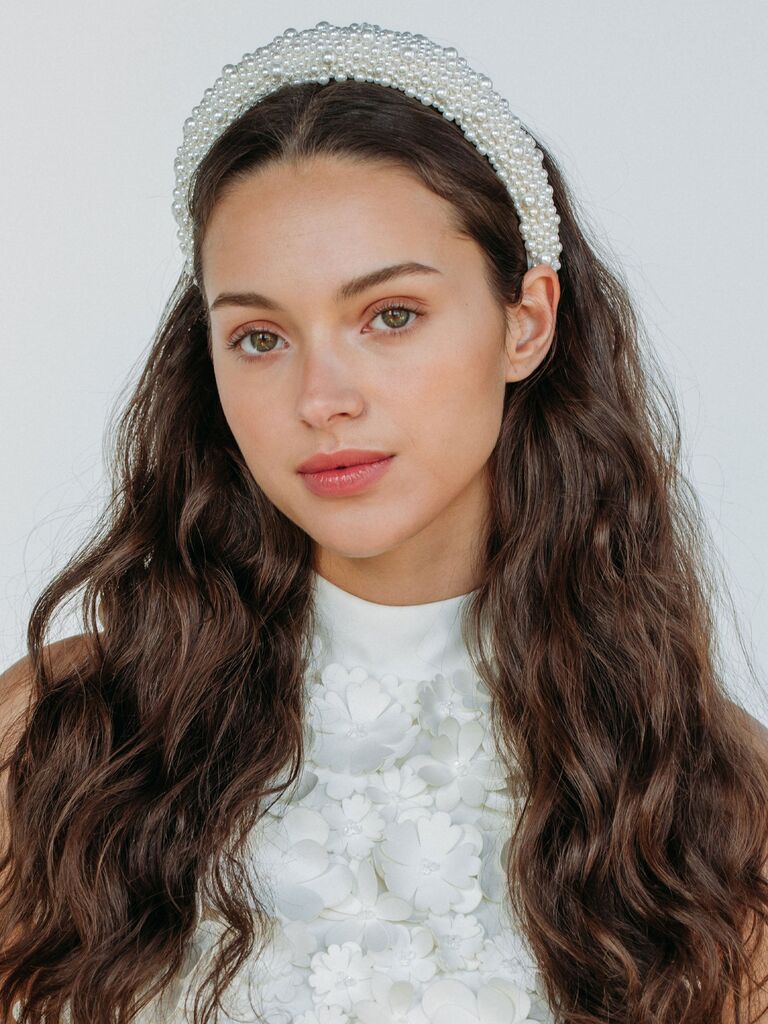 Model wears a chunky white headband embellished with pearls. 