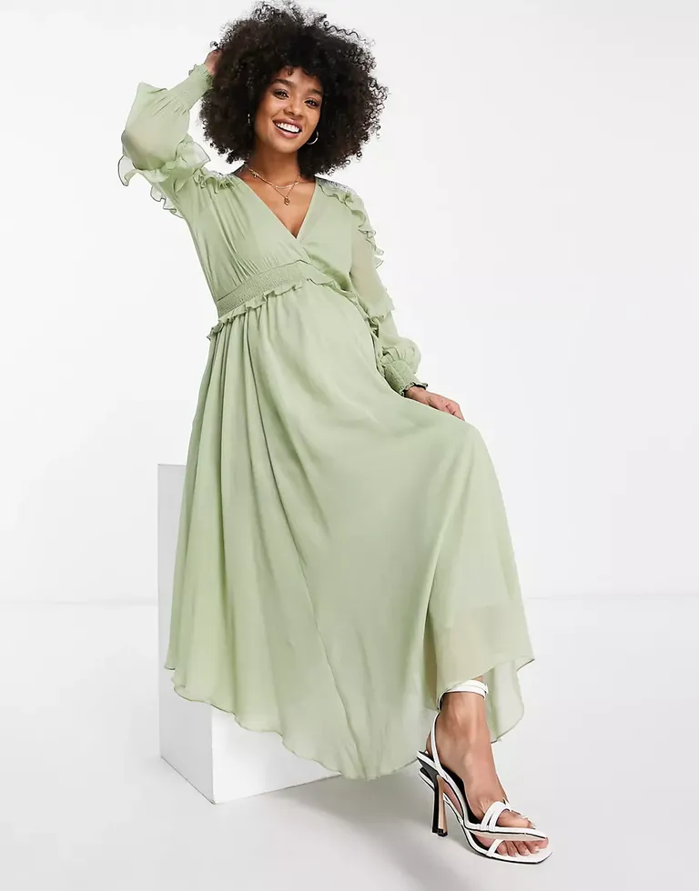 Model wears a sage green maxi-dress with ruffled long sleeves. 