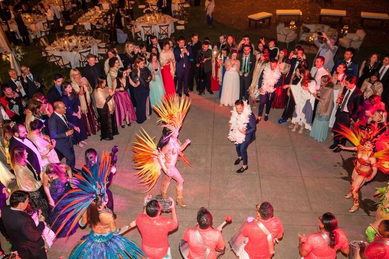 Weddings guests encircle the groom and a traditional dancer.